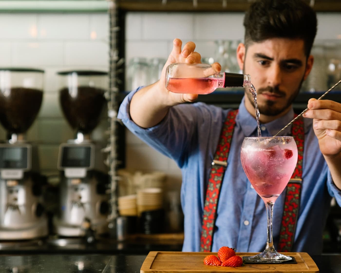 Male bartender pouring tonic into serve with berry garnish