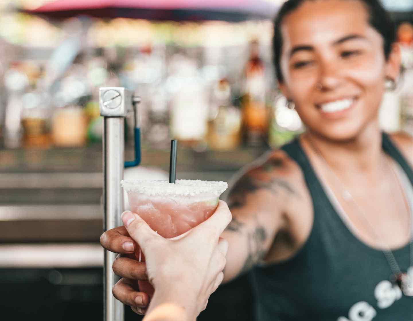 Smiling bartender serves a cocktail