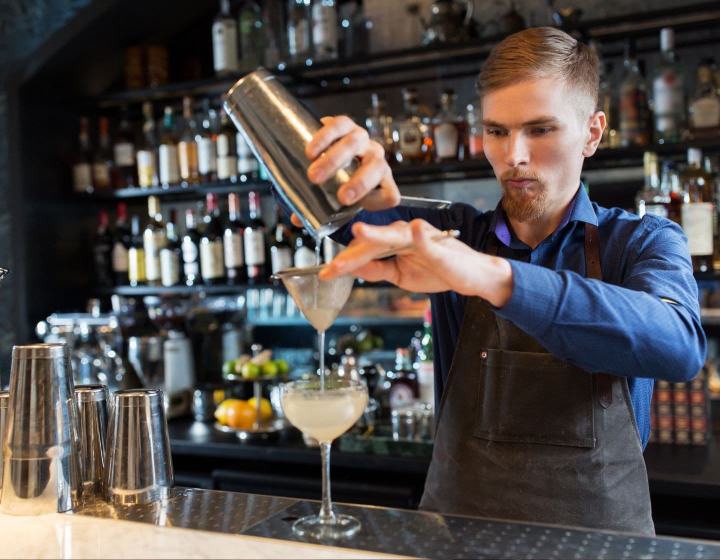 Bartender pouring cocktail from shaker into cocktail glass