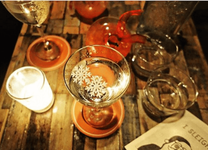 Ein Drink steht neben einer Kerze und anderen Gläsern auf einem Holztisch