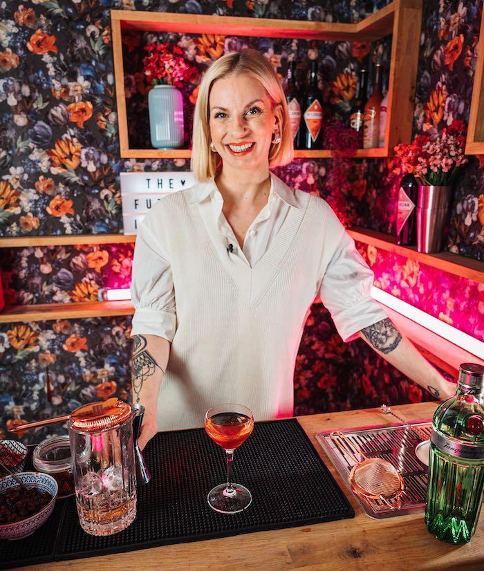 Dominique Maria Krauß steht an einer rosa Bar