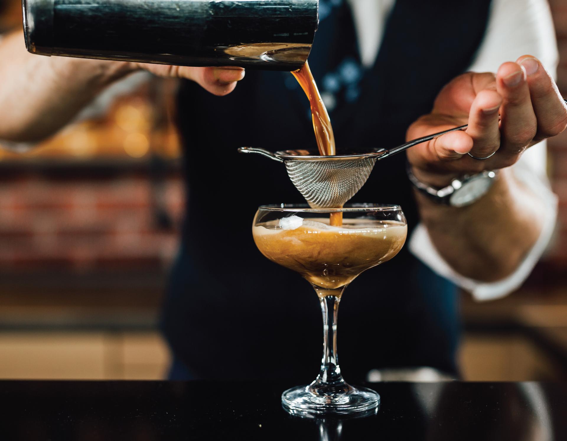 Cocktail poured from shaker into a glass.