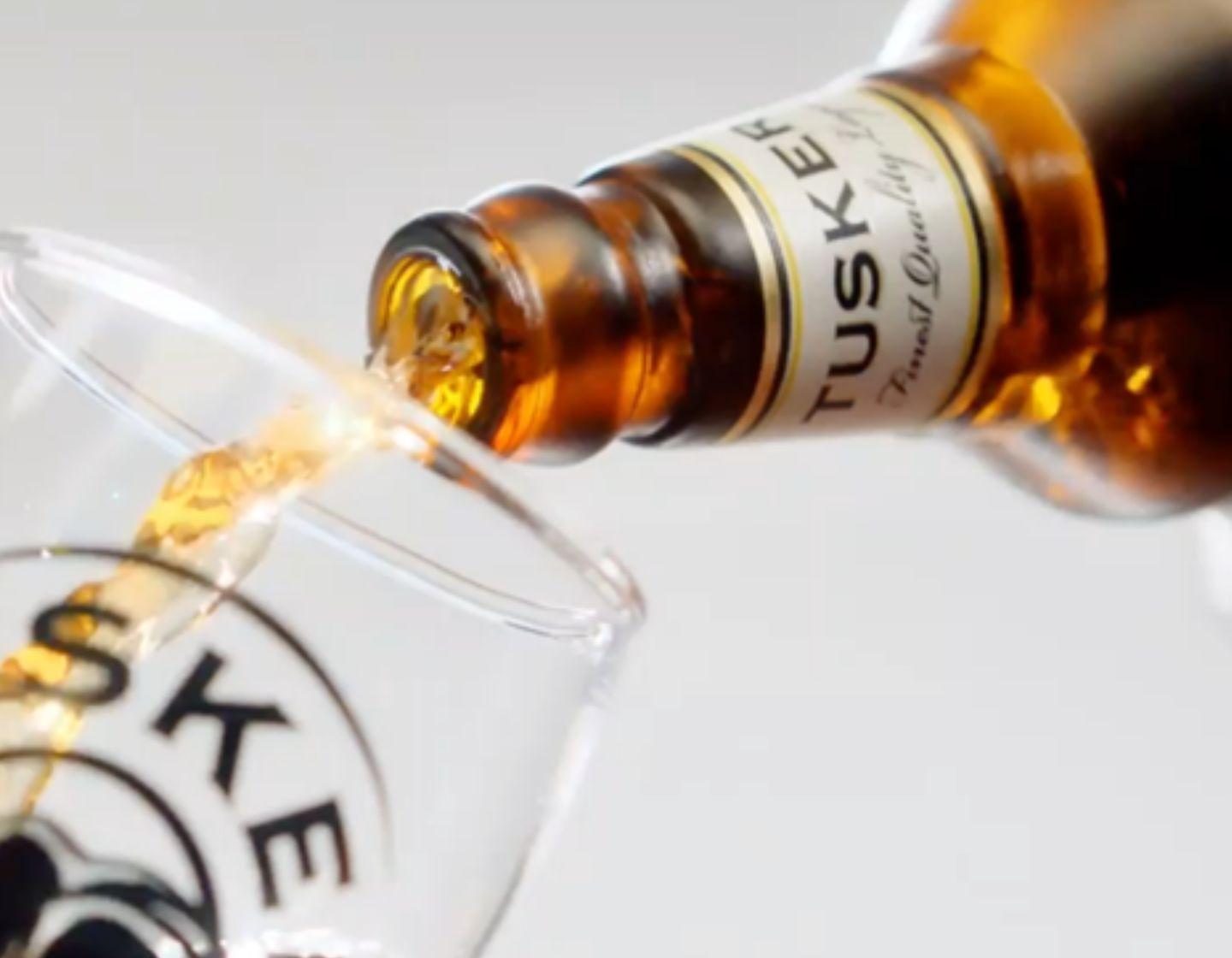 Tusker Beer being poured into a logo beer glass. 