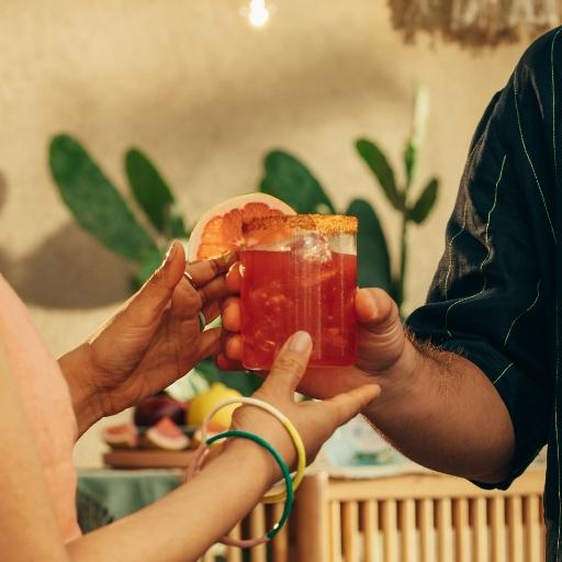 Blood orange magarita in glass with garnish and customers hands