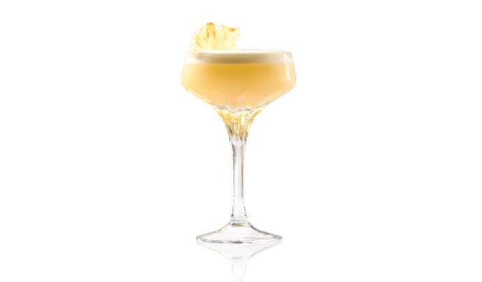 Vodka sour in coupe glass with foam and pineapple garnish