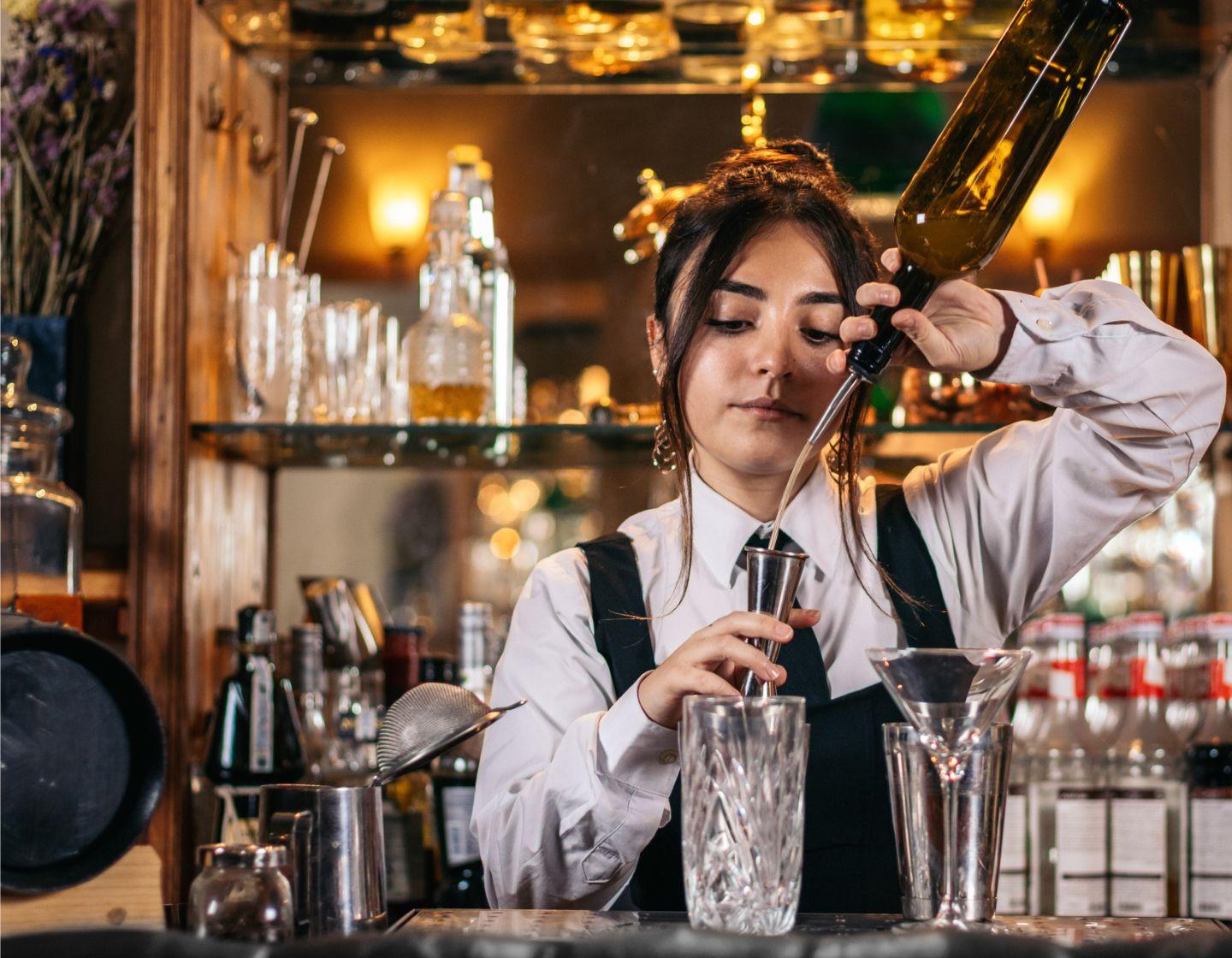 Bartender sirviendo con una botella en un vaso