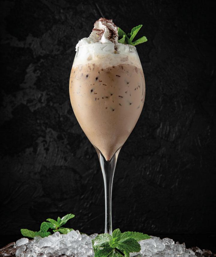 Cóctel a base de Baileys adornado con crema batida fresca y menta
