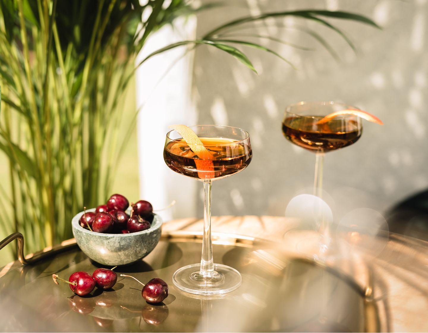 Two rum cocktails next to a bowl of cherries 