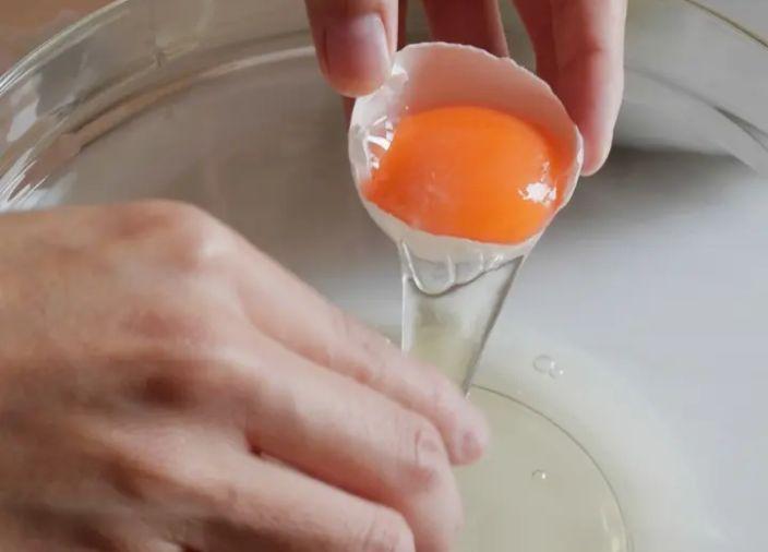 Person cracking egg into a bowl and separating egg whites