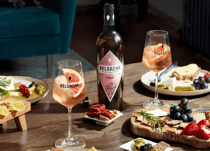 Botella de Belsazar junto cócteles y unos platos de comida