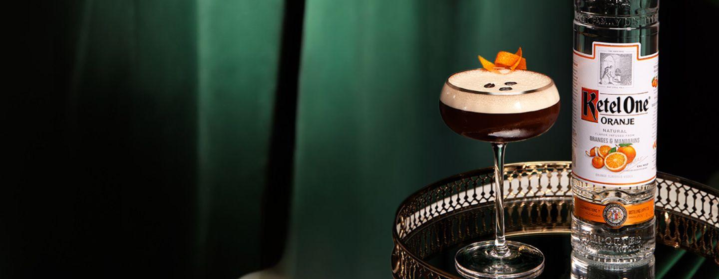 Cocktail in a coupe glass with a bottle of Ketel One