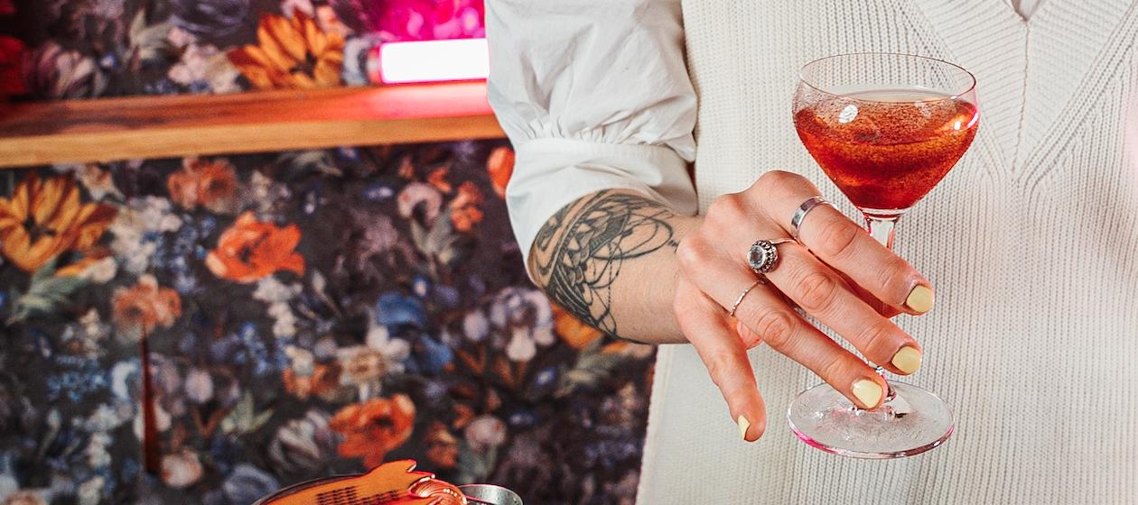 Dominique hält einen rosa Cocktail in der Hand