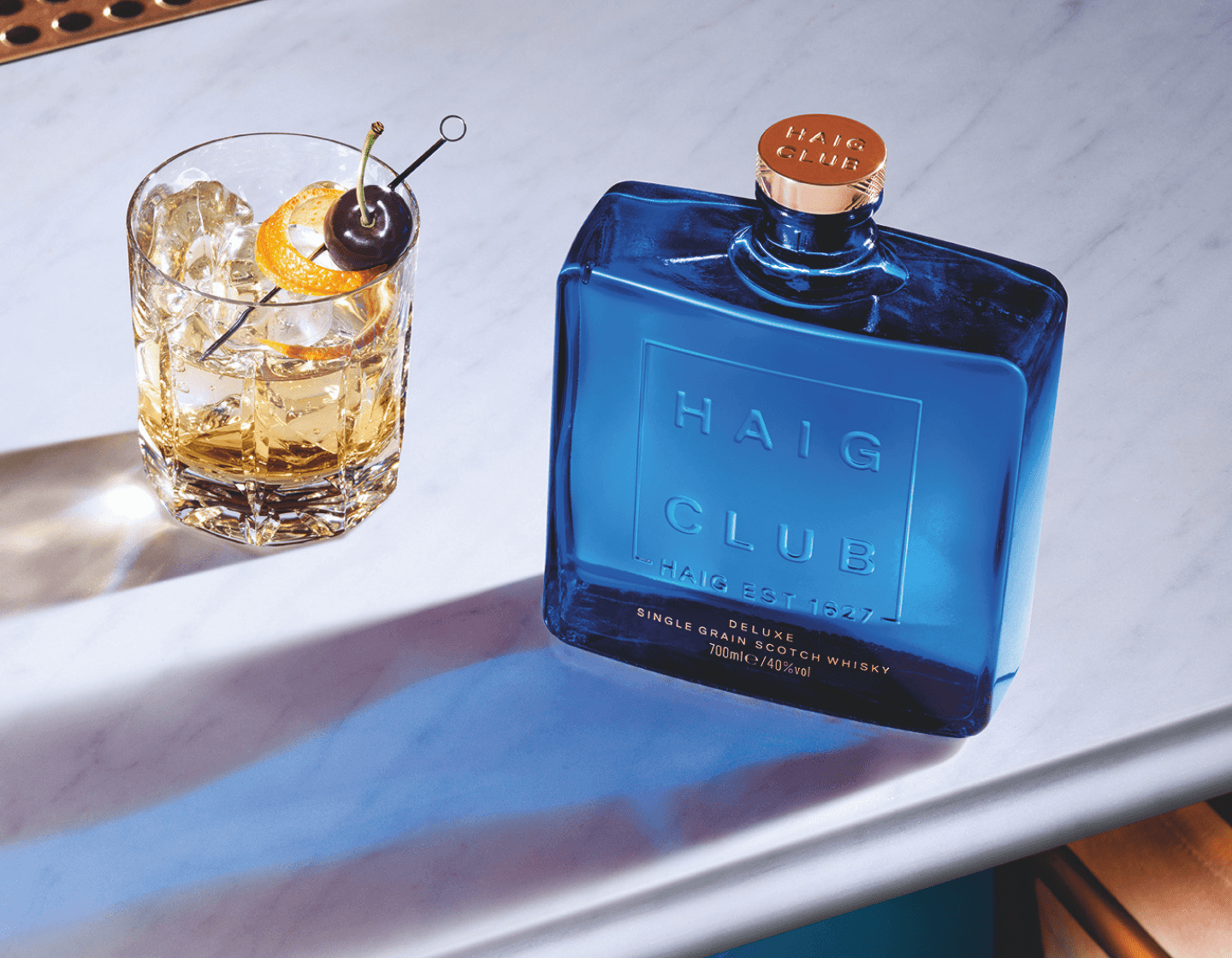 Bottle of Haig Club Single Grain Scotch Whisky next to a cocktail. 
