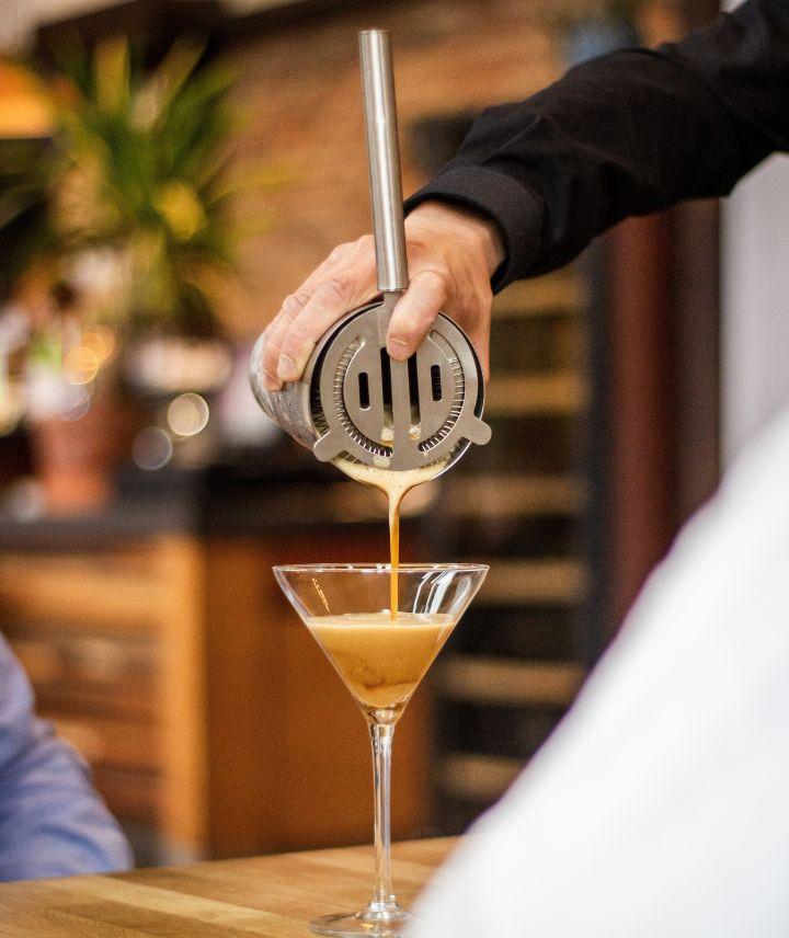 imagem de um bartender coando um drink