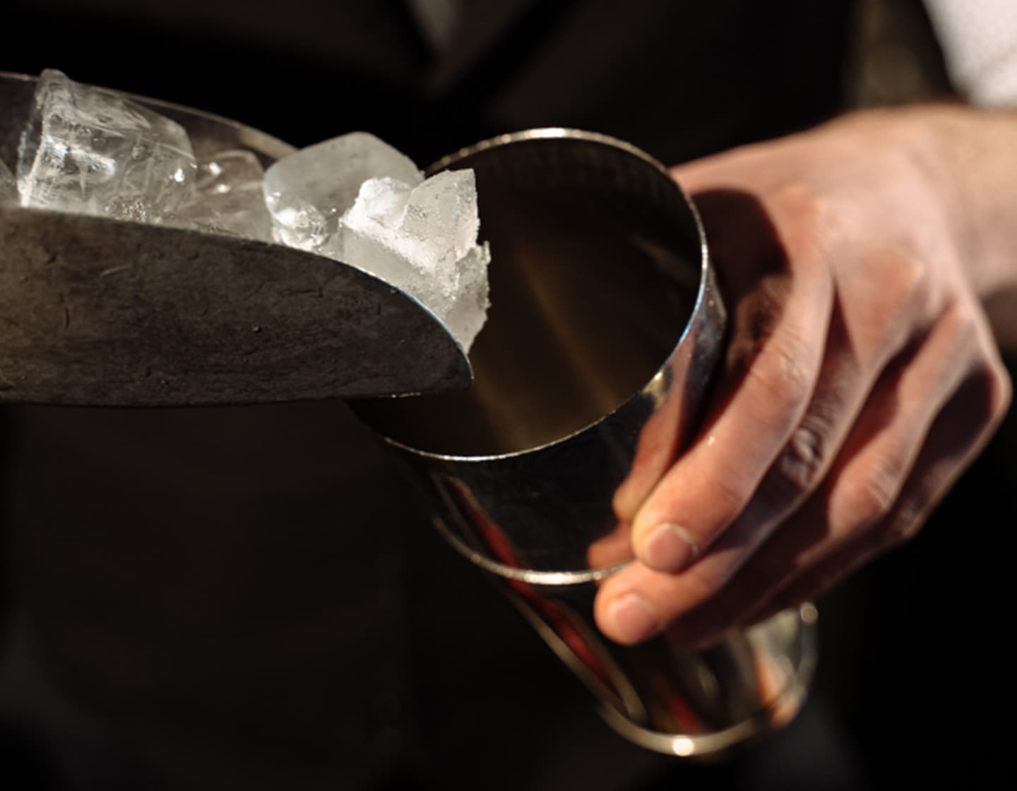 Ein Barkeeper gibt Eis in einen Cocktailshaker.