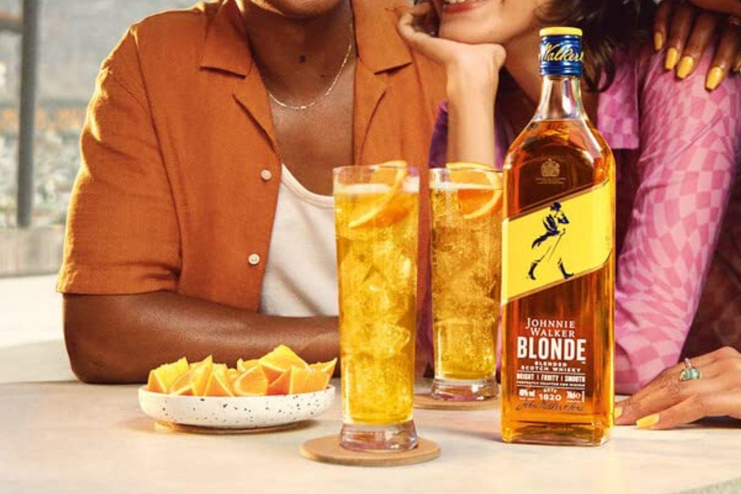Botella de JW Blonde con dos hoghballs y dos personas disfrutando de una picada