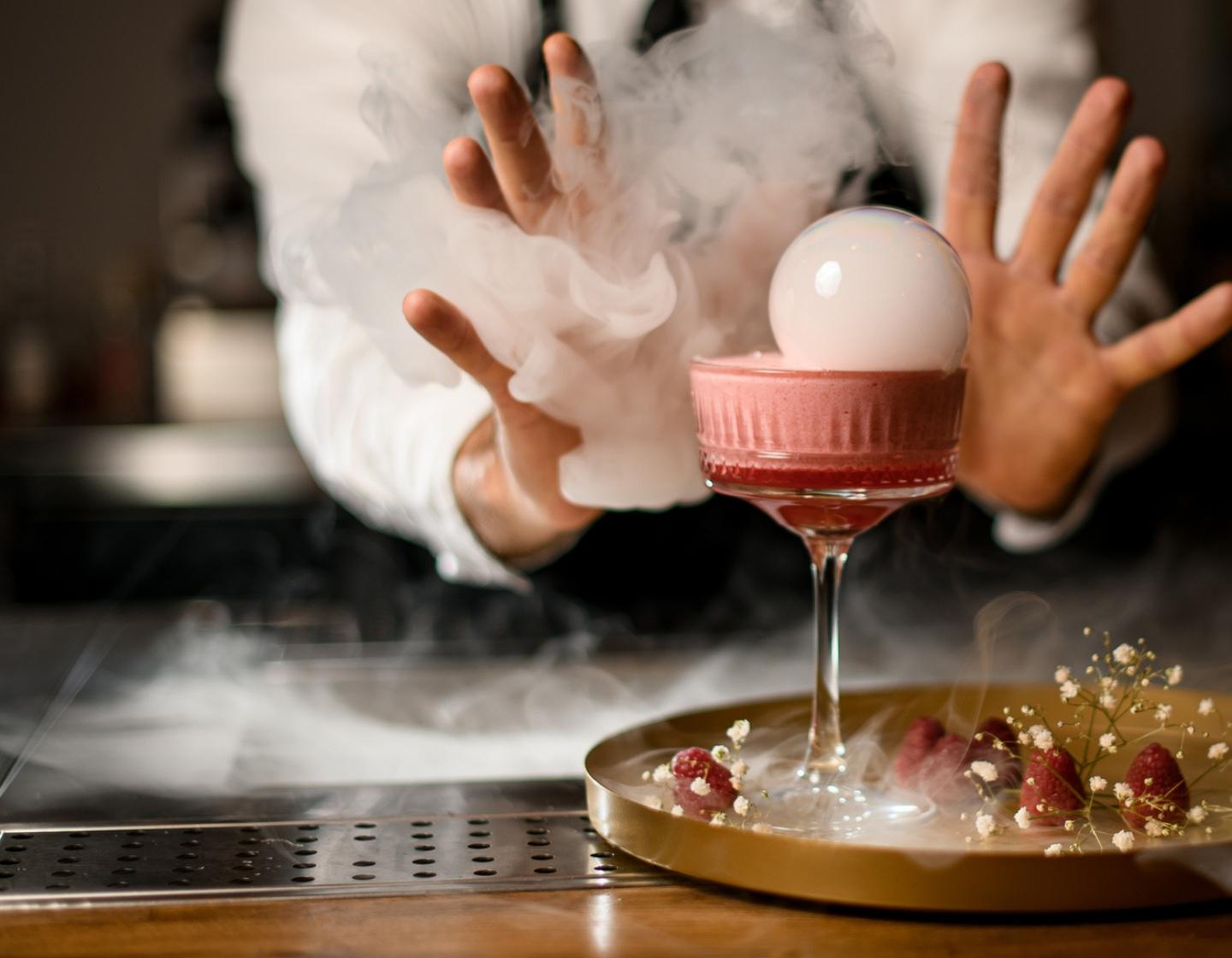 Un bartender sirviendo un cóctel con humo