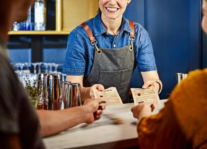 Waitress handing menus to two customers