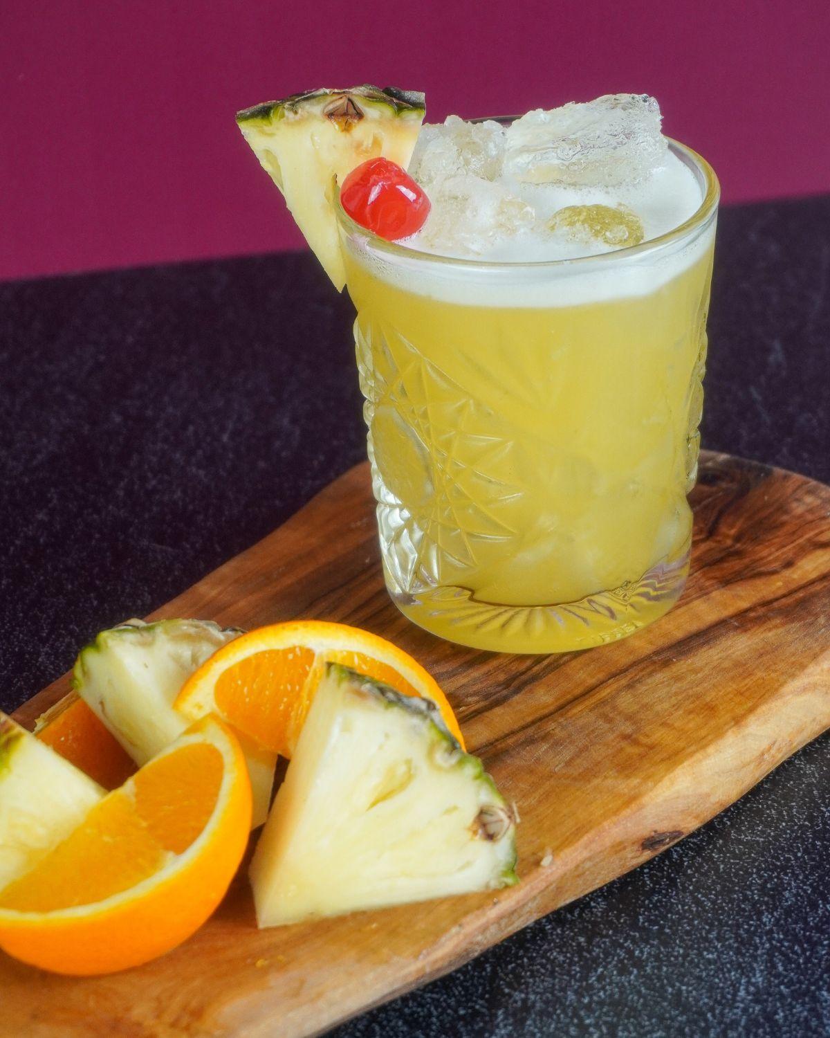 Pineapple Rum Punch con piña y gajos de naranja como garnish