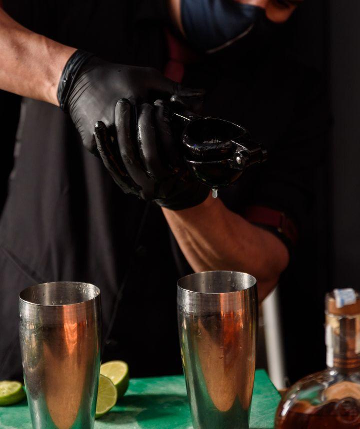 Imagem de uma bartender manipulando drinks com luvas