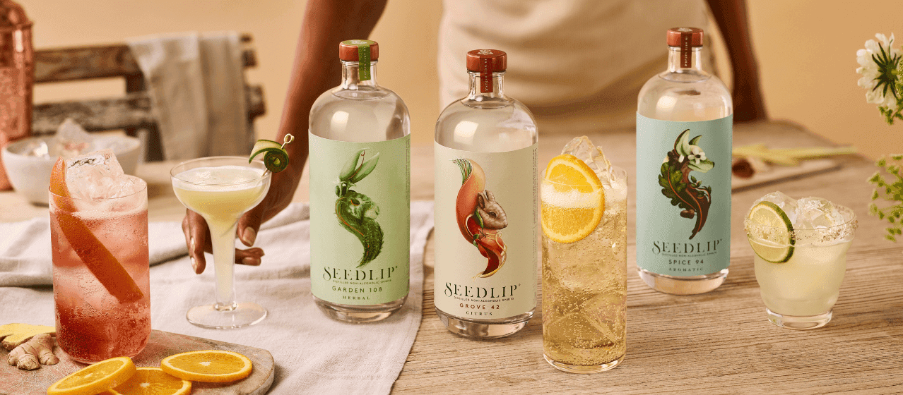Auswahl an Seedlip-Flaschen auf dem Tisch, umgeben von verschiedenen Cocktails