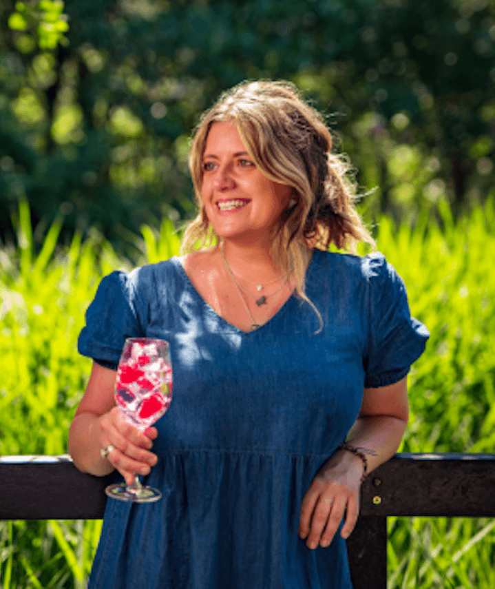 Blonde Person in der Natur mit einem Cocktail in der Hand