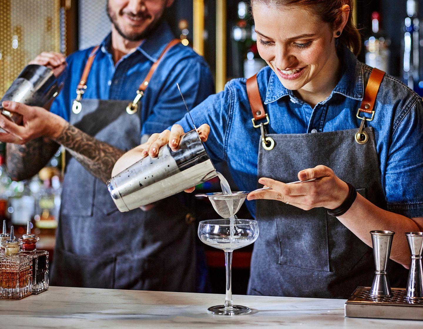 Two bartenders pouring cocktails
