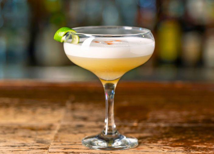 Yellow cocktail in a glass on a wooden countertop. 