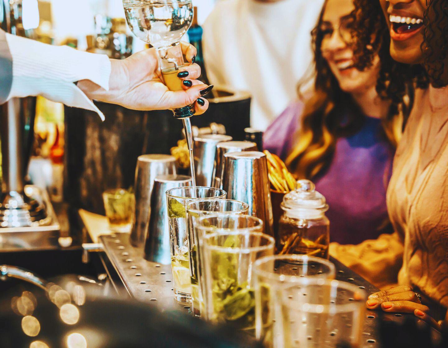 Bartender sirviendo cócteles frente a los clientes en un bar.