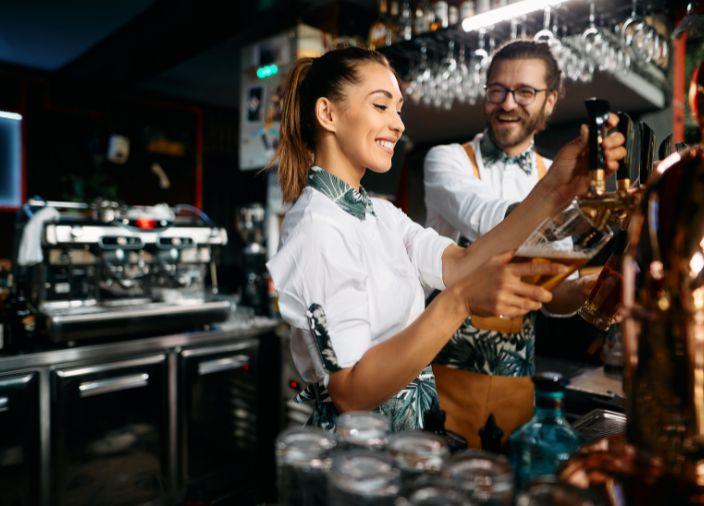 Bar com várias estações e dois bartenders sorridentes  