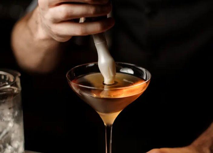 Bartender using siphon to add foam to top of cocktail