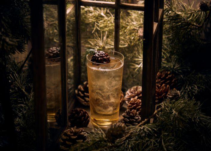 Un cóctel alto rodeado de piñas y cubierto con un garnish de piña de chocolate.