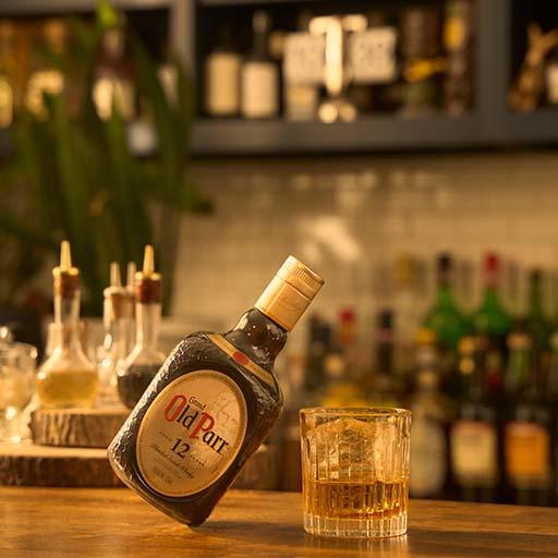 Bottle of Old Parr on table with cocktails