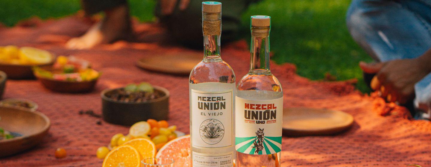 Two Mexcal Union bottles on a picnic blanket