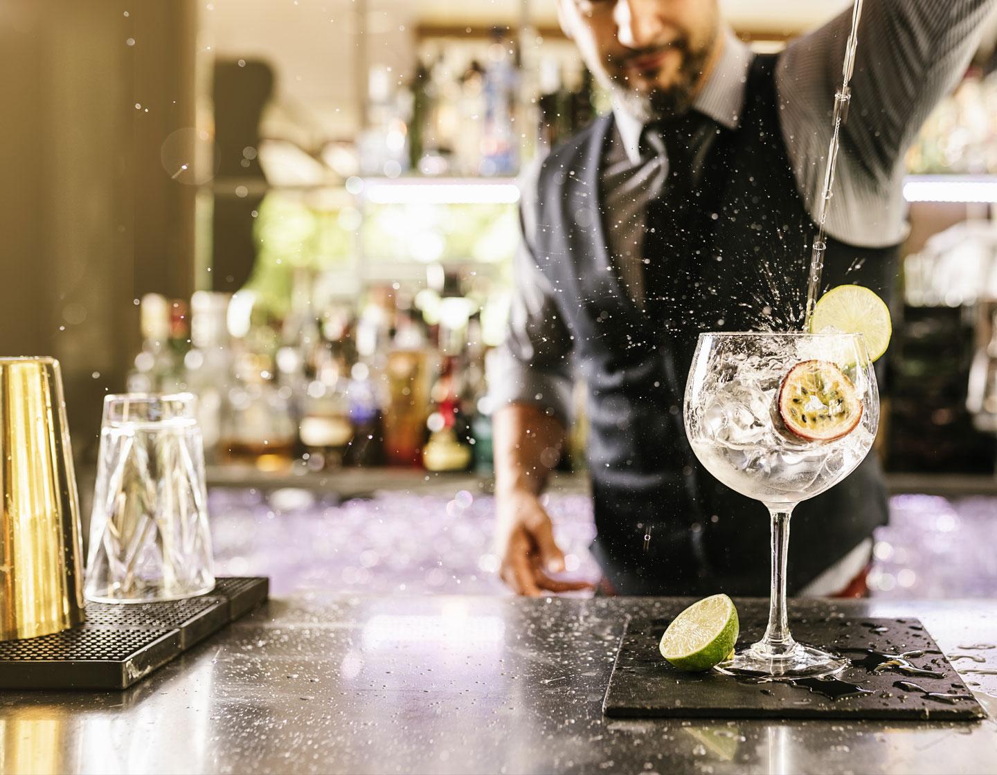 bartender vertiendo un líquido en una copa de balon