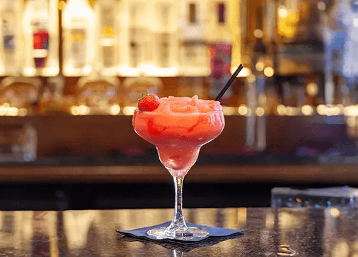 Ein oranger Drink steht vor einer Bar