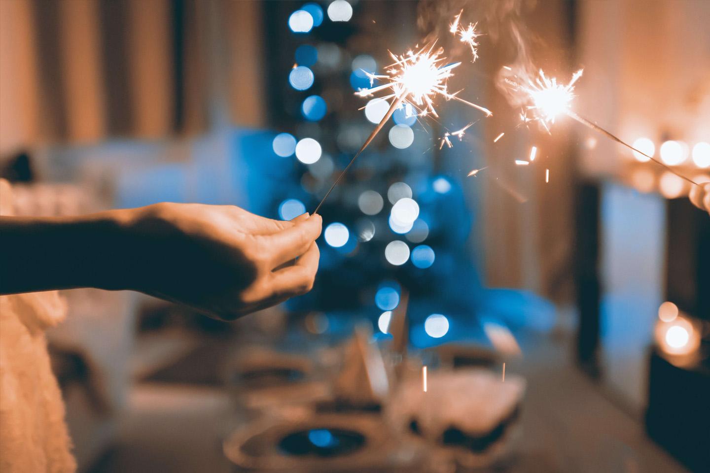 uma mão segurando uma vela estrelinha com um fundo desfocado mostrando um bolo de aniversário