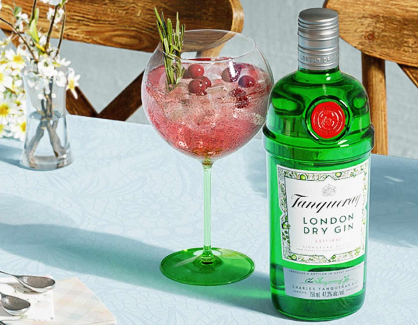 Tanqueray London Dry Gin bottle next to red cocktail with berries
