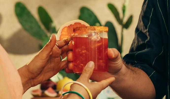 Blood orange magarita in glass with garnish and customers hands