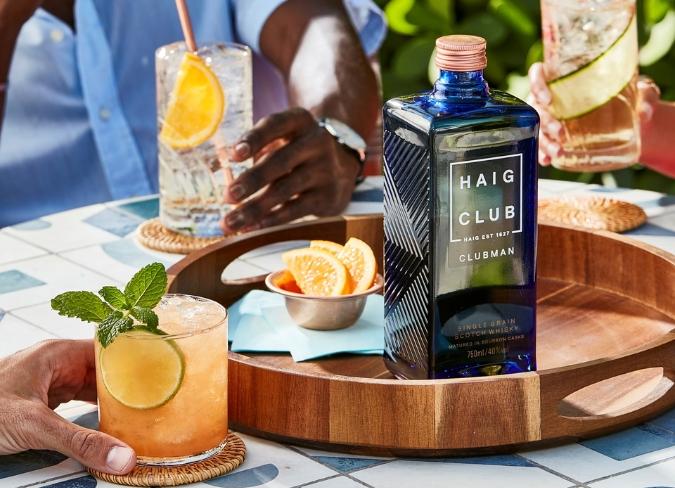 Bottle of Haig Club on tray surrounded by cocktails and garnishes