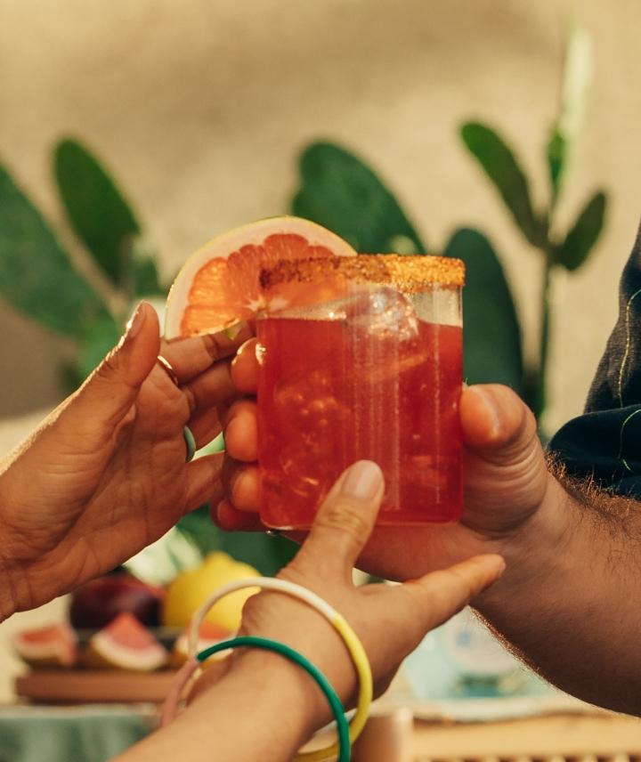 Blood orange magarita in glass with garnish and customers hands