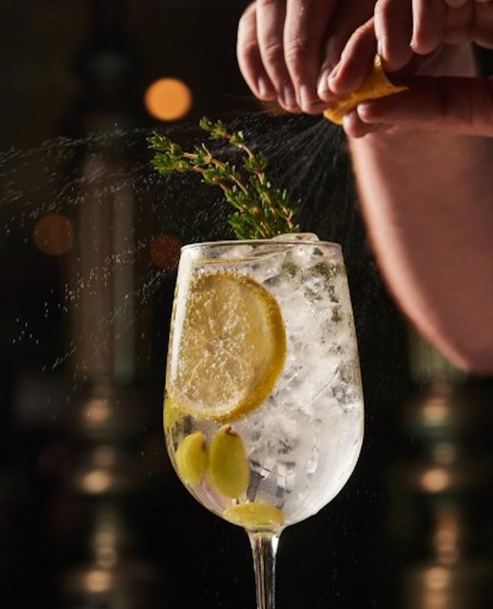 Cocktailglas mit Eis, einer Zitronenscheibe und Zitronenspritzern