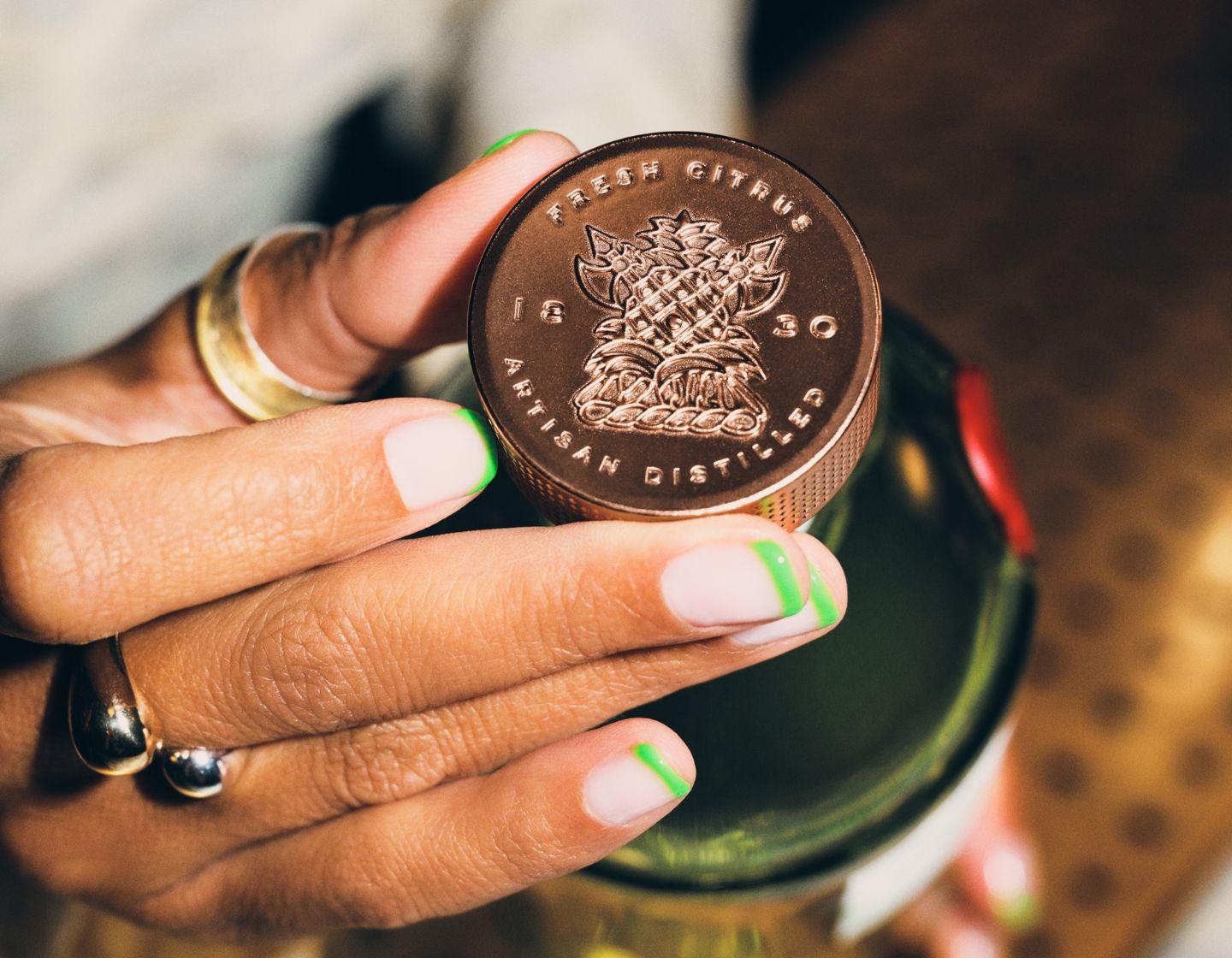 Tanqueray No. TEN bottle top with hands.