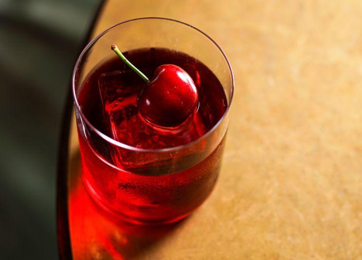 Un cóctel negroni con garnish de cerezas.