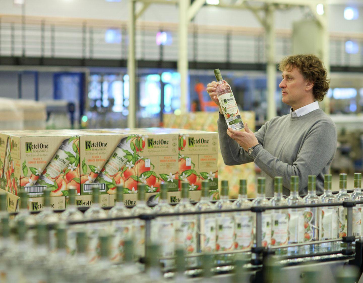 Man looking at Ketel One Vodka bottle in distillery