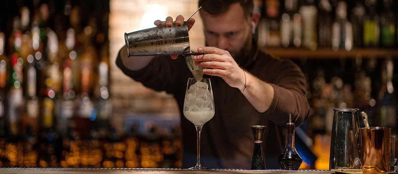 Barkeeper gießt Drink ins Glas