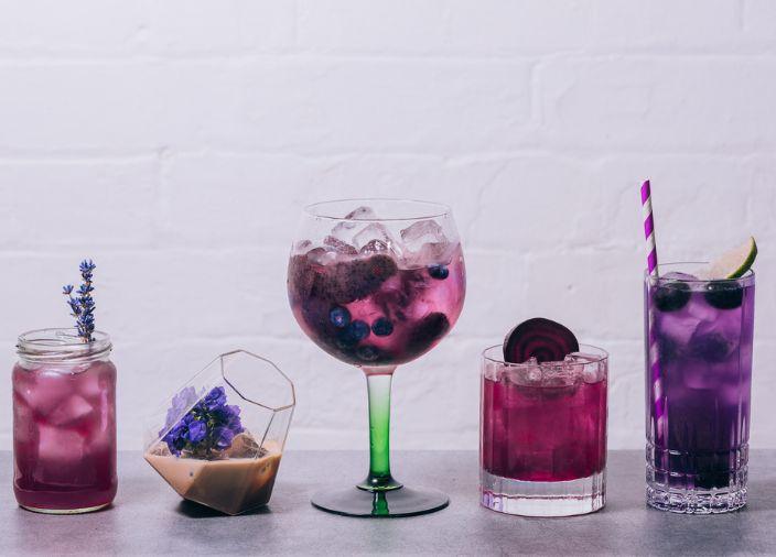 Colección de 5 cócteles diferentes con morado en líquido o garnish.