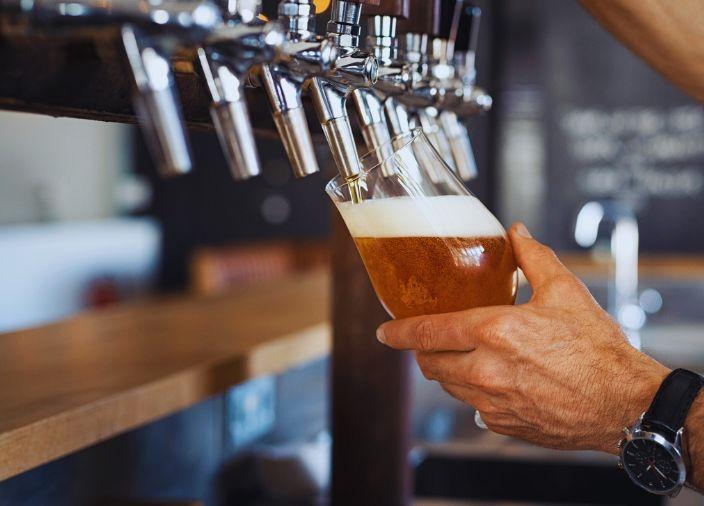 Glass of beer being poured from a row of bar taps.