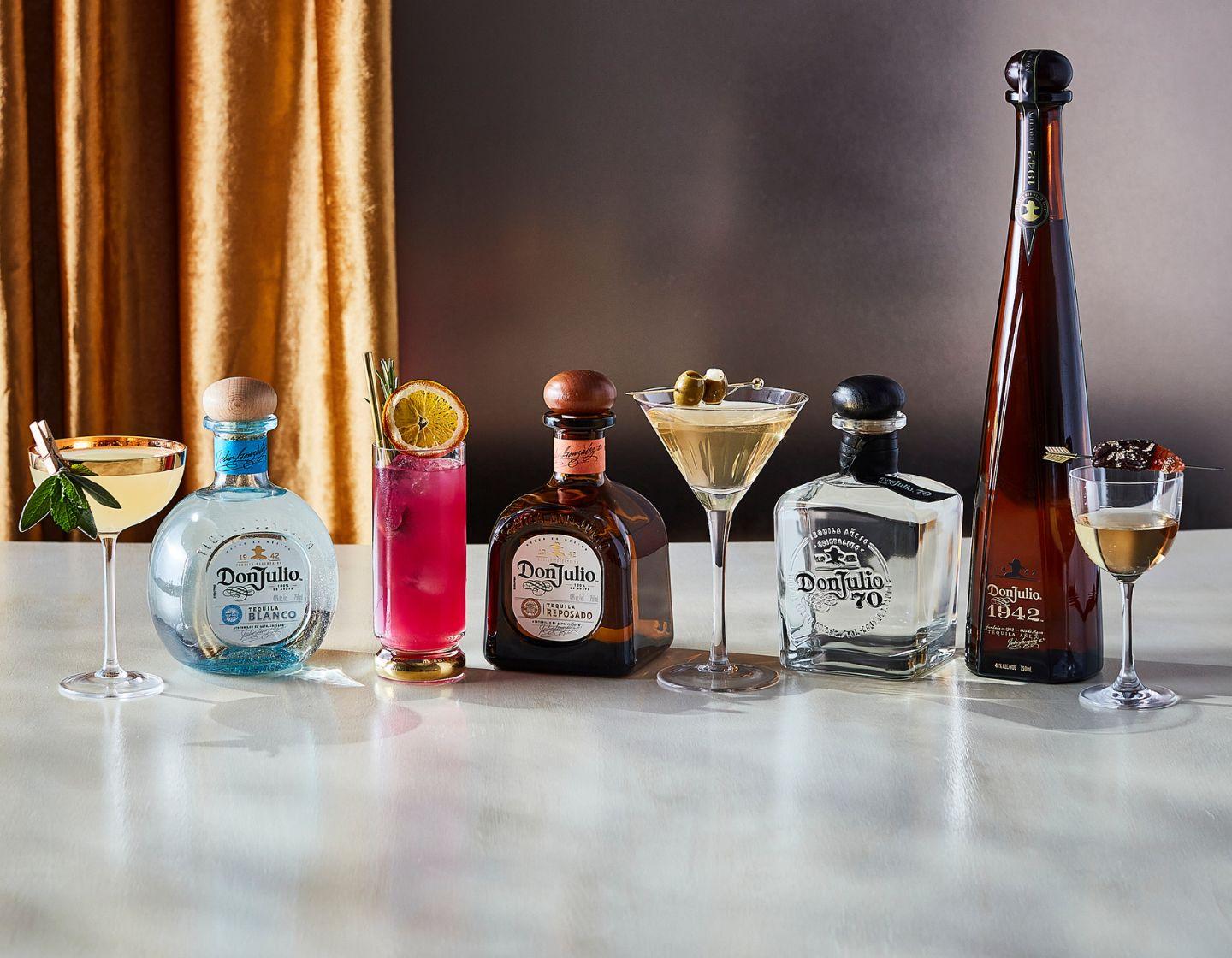 Seleção de diferentes garrafas de tequila Don Julio posicionadas sobre mesa de madeira 