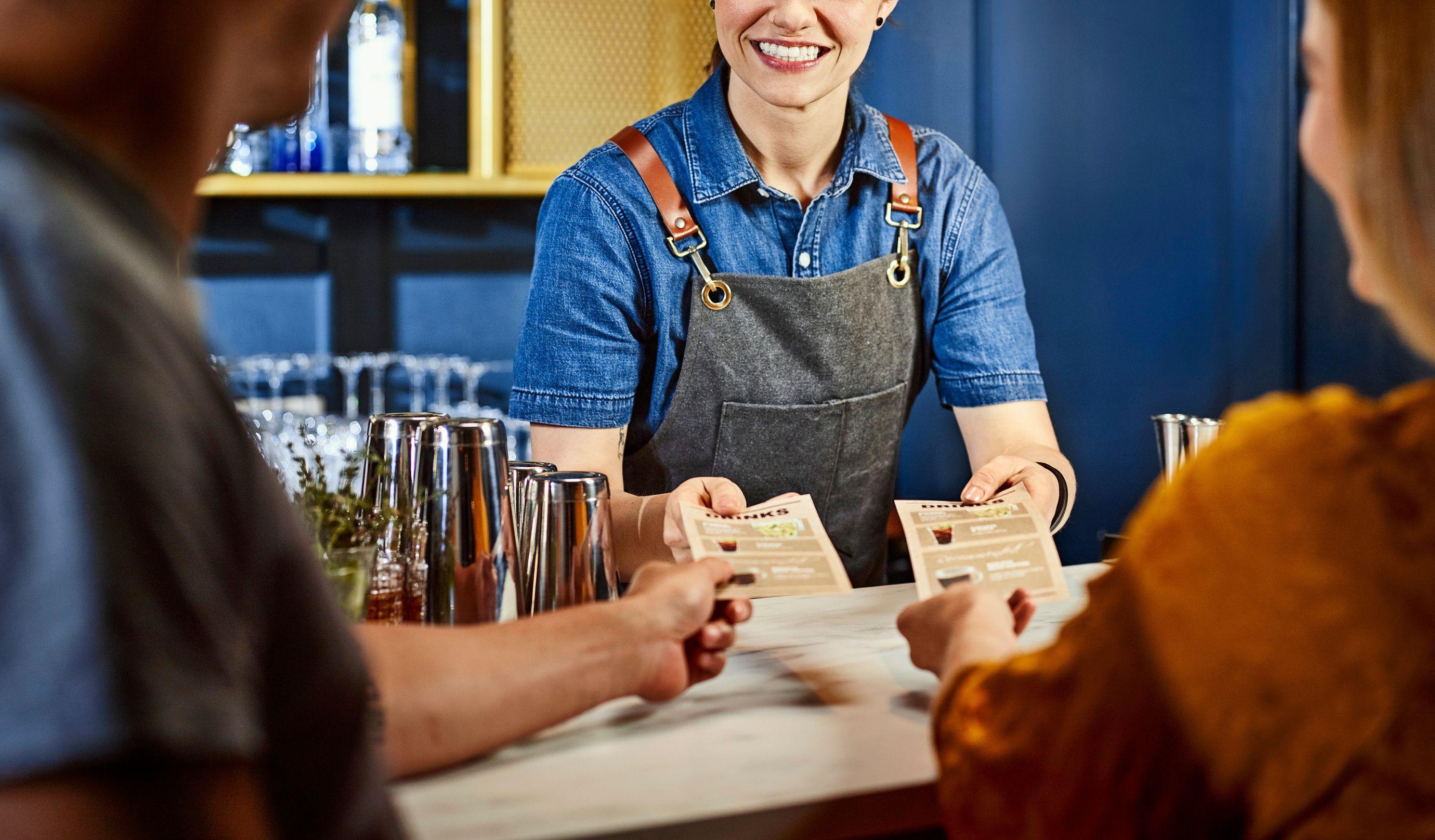 Bartender mostrando menus a los clientes